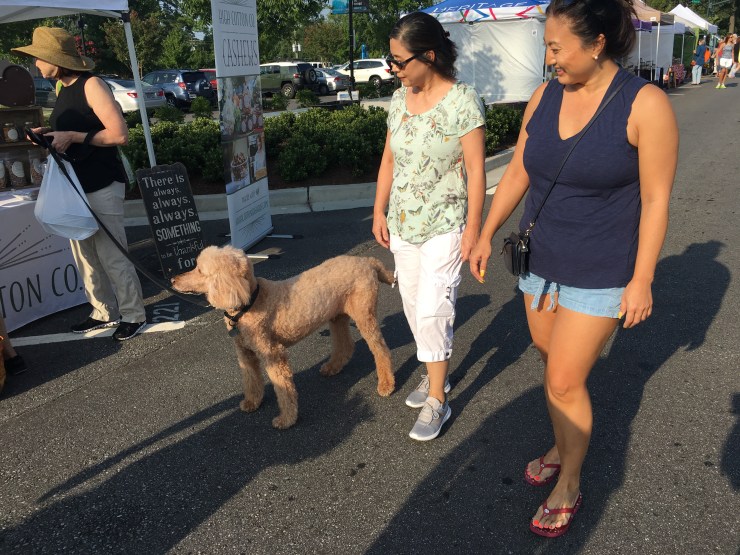 Two women smiling at a dog.