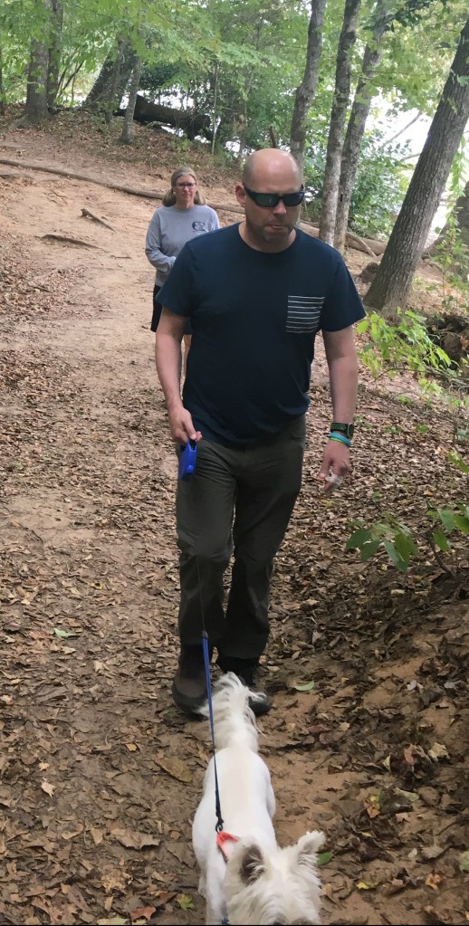 Couple walking a dog in the forest.