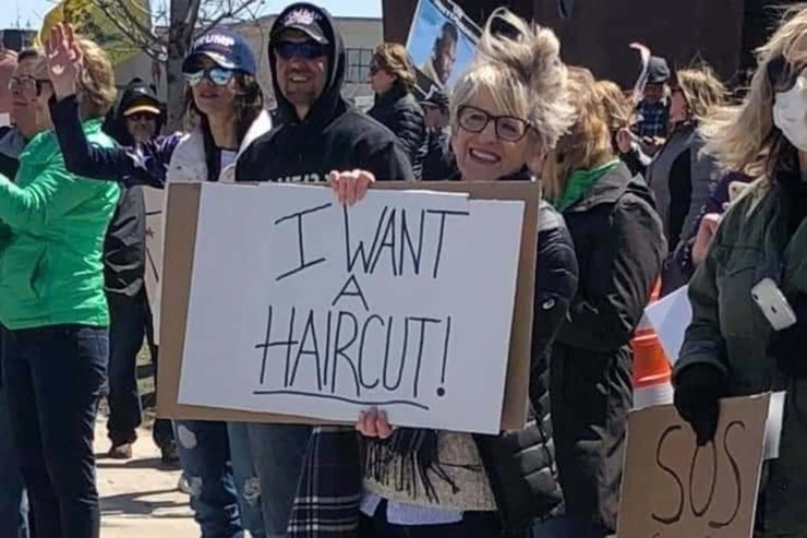 Protestor holding sign that says “I want a haircut”