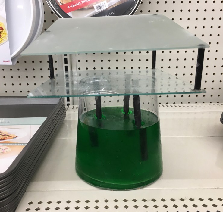 “Cookware Conflict”: glass and wood mounted on jello filled vase.