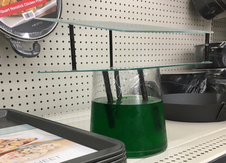 “Cookware Conflict”: glass and wood mounted on jello filled vase.