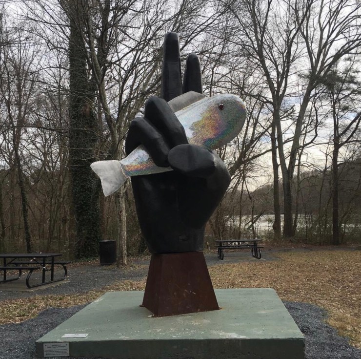 Sculpture of giant hand holding a a giant fish.