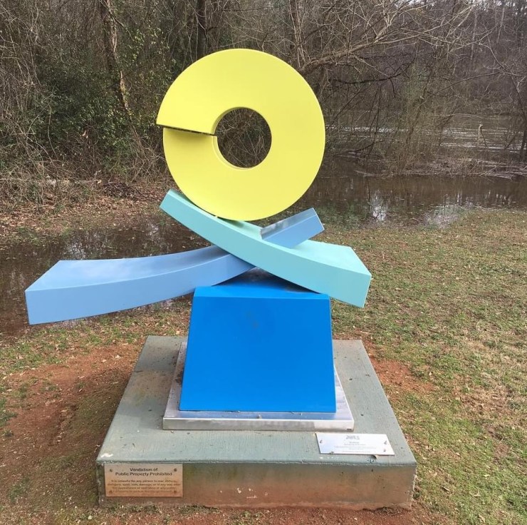 Blue and yellow abstract statue in a park.