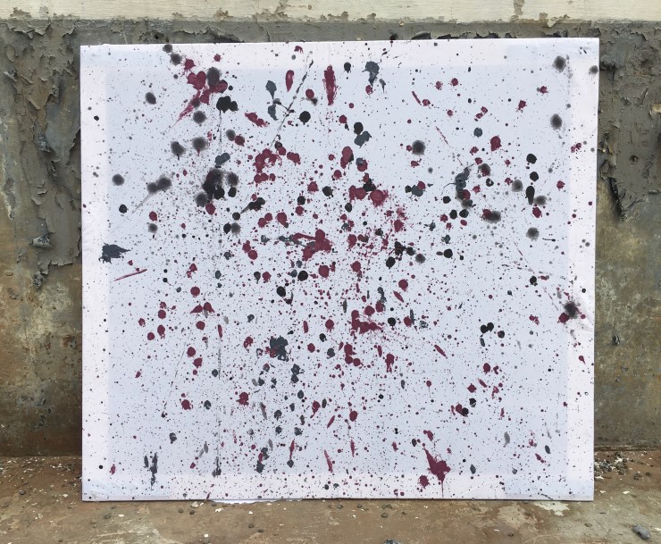 Marbles dipped in black, gray and burgundy paint dropped on a canvas.