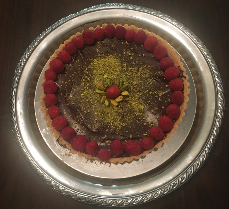 A chocolate tarte with raspberries and ground pistachios.