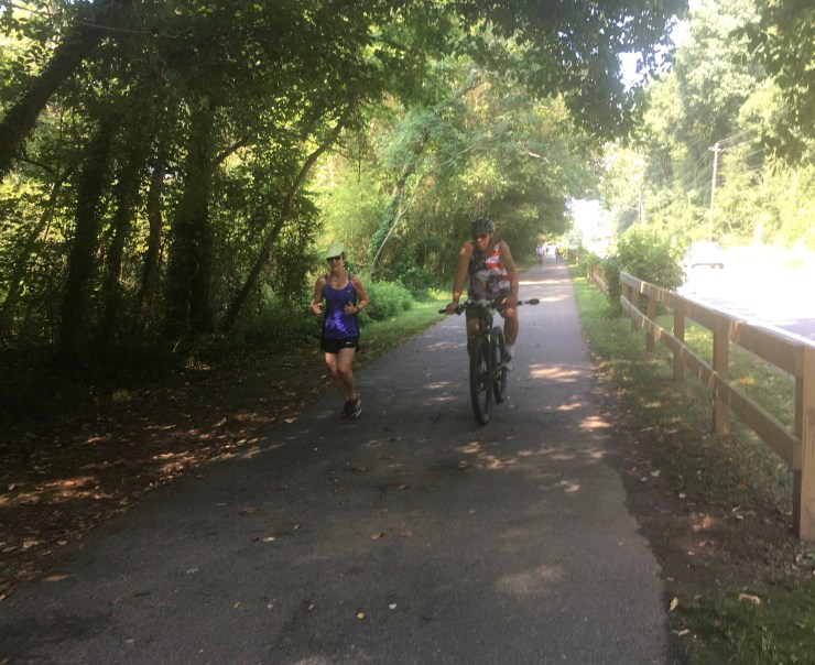 Jogger next to a cyclist on a mixed use path.