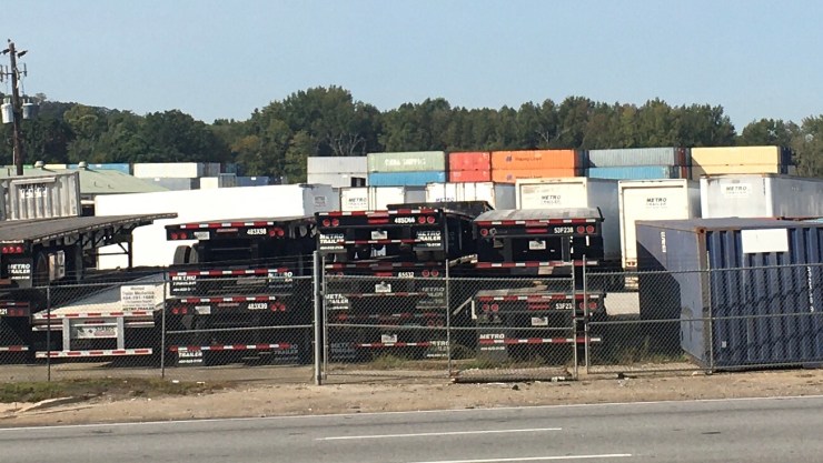 A yard of empty trucks stacked on each other.