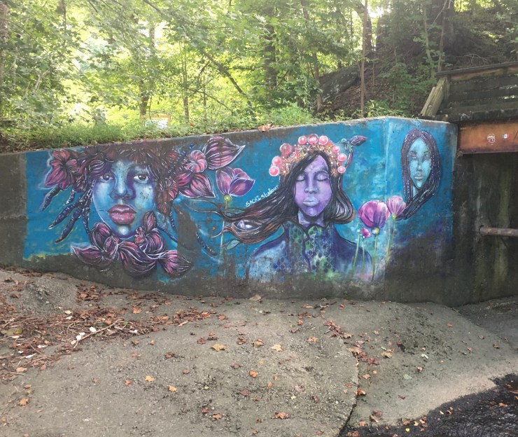 Mural of women’s faces on a bridge.