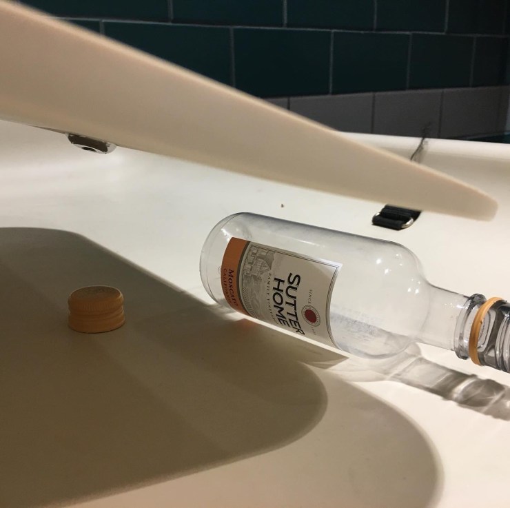Empty wine bottle on a diaper changing station.