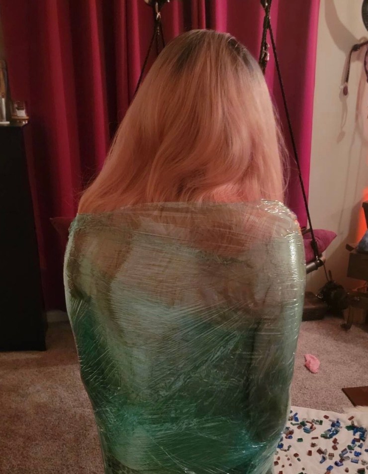 Woman wrapped in cling film seen from behind.