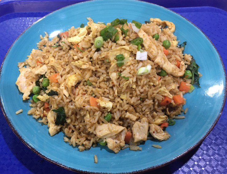 A plate of fried rice with peas and carrots.