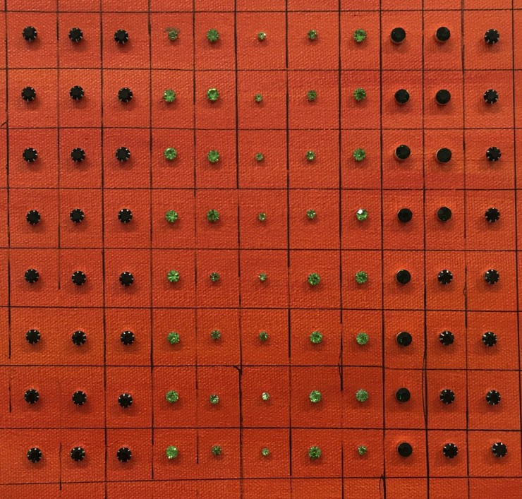 Green earrings on an orange canvas.