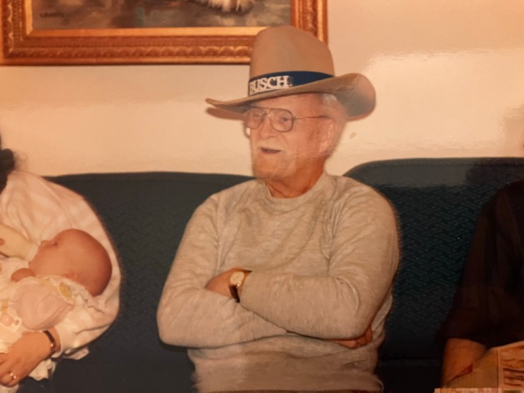 My grandfather with his arms folded and wearing a Busch beer cowboy hat.