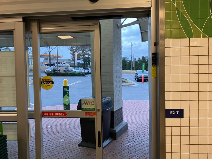 Automatic door in a grocery store lobby opening to a parking lot.