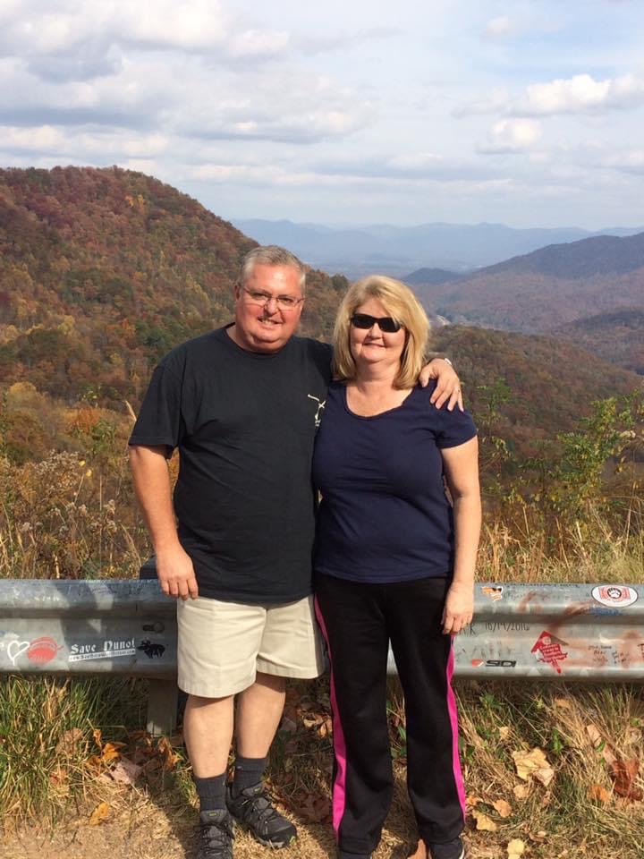 Jim H’s brother and his wife standing in front of a mountain range.