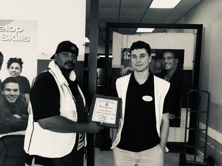 Black and white photo of an African American man handing an award to a Caucasian man.